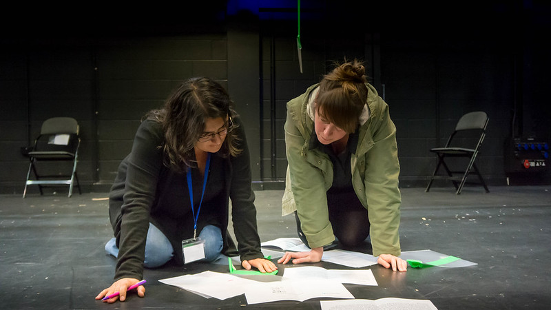 Two people kneeling on the floor and looking and papers