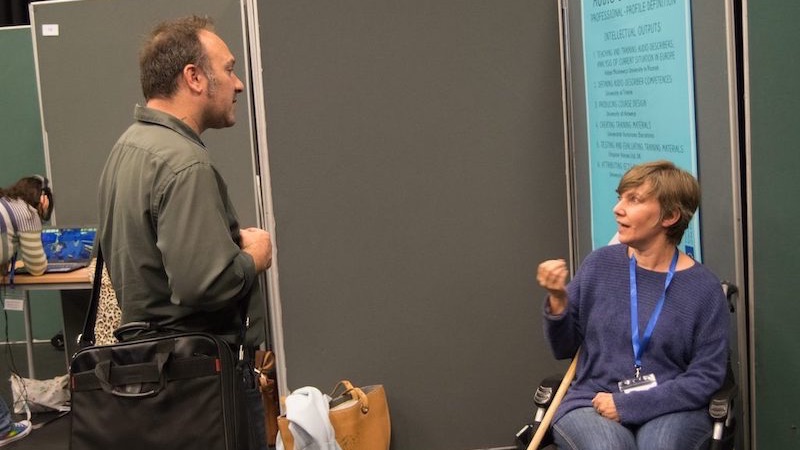 Two conference attendess talking next to a poster